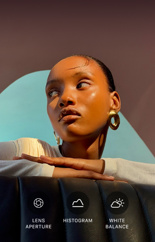 A person with their head turned to the side, bright light shines on them from opposite direction, their hands overlapped on a flat surface in front of them at shoulder height, three photo controls: Lens Aperture, Histogram, and White Balance
